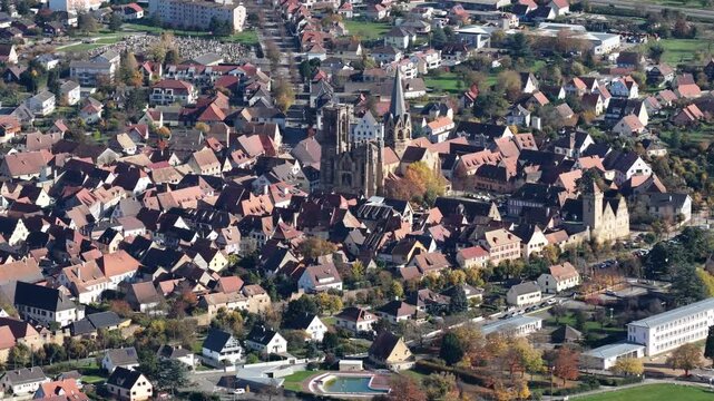 Aerial view of tightly packed buildings, including a church with a tall spire, creating a dense urban landscape, Rouffach, Grand Est, France.