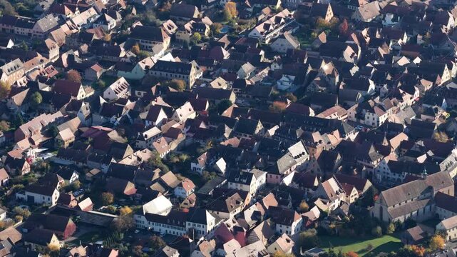 Aerial view of closely packed red-tiled rooftops and buildings creating a textured landscape, showcasing the urban sprawl, Rouffach, Grand Est, France.