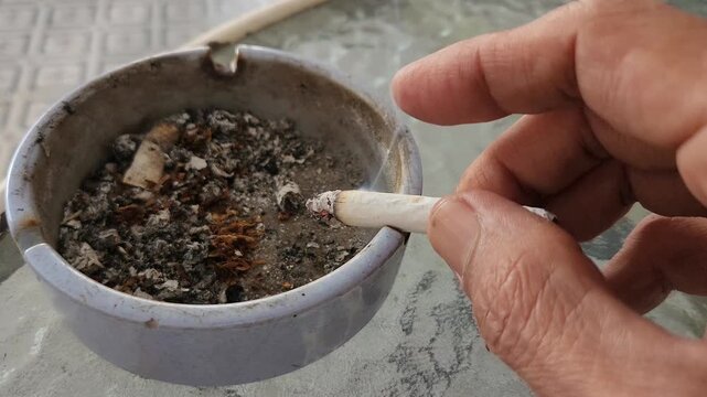 Close-up of a cigarette being extinguished in an ashtray full of ash
