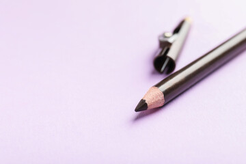Color eye pencil and sharpener on pink background, closeup. Space for text