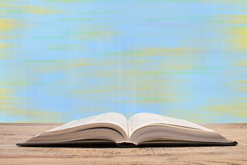 Composition with hardback books, fanned pages on wooden deck table and blue background. Books stacking. Back to school. Copy Space. Education background.