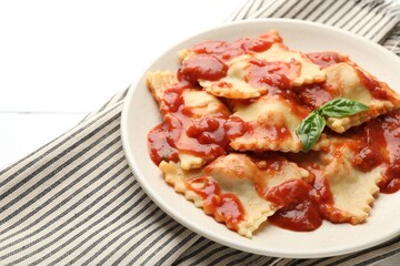 Delicious ravioli with tomato sauce and basil on white wooden table, closeup. Space for text