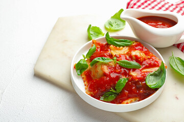 Delicious ravioli with tomato sauce and basil on white table. Space for text