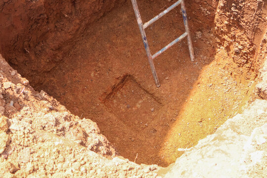 Foundation excavation with a smaller pit for auspicious first brick laying ritual, showing cultural customs in new home construction and Bhoomi Puja practices.