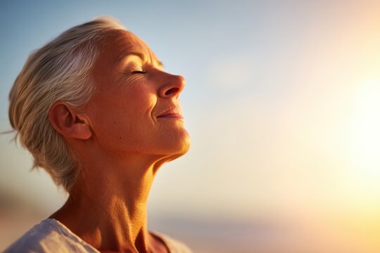Peaceful Senior Woman Enjoying Sunset with Eyes Closed on Beach.