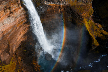 Aerial view shows Haifoss waterfall plunging into a misty canyon in Iceland. Stratified basalt...