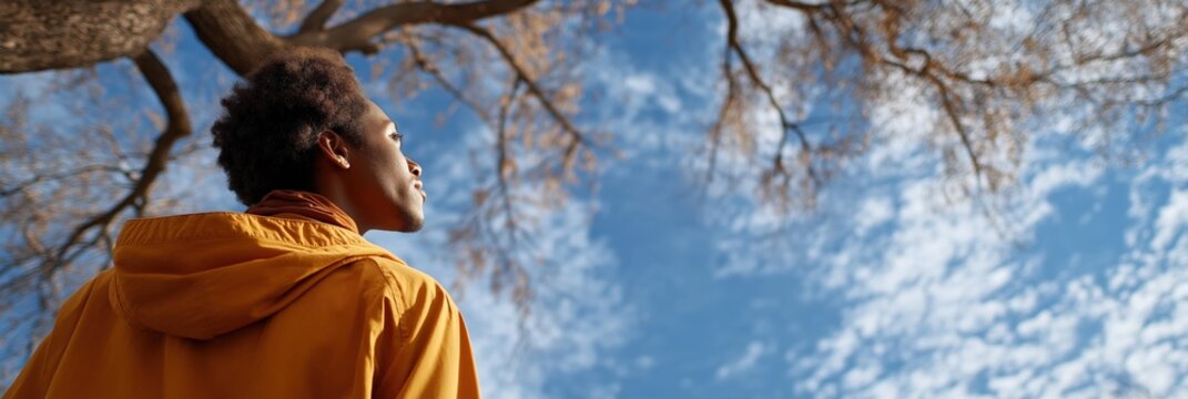 Young african male reflecting under autumn sky with bare trees