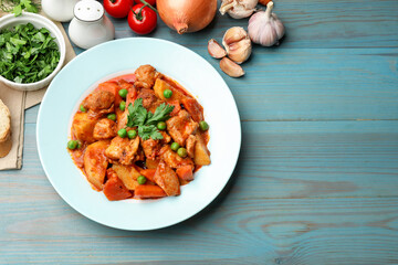 Delicious cooked stew and ingredients on light blue wooden table, flat lay. Space for text