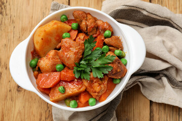 Delicious cooked stew in bowl on wooden table, top view