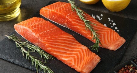 Pieces of salmon fillet and spices on grey table, closeup