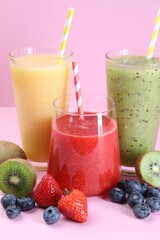Different tasty smoothies in glasses and ingredients on pink background, closeup