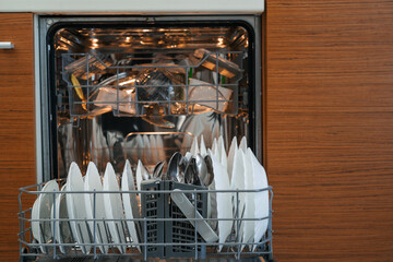 Open dishwasher with neatly arranged clean dishes and cutlery