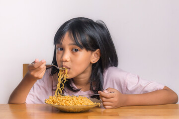 A little Asian girl enjoying eating fried noodles at home