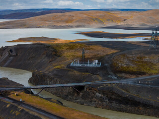 Aerial view shows a steel suspension bridge over a milky glacial channel near Sigoldugljufur in...