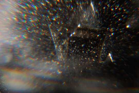 Easy to add lens flare effects for overlay designs or screen blending mode to make high-quality images. Abstract sun burst, digital flare, iridescent glare over black background. Defocused dark bokeh.