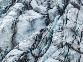 Extreme close up of glacier ice in Iceland shows jagged ridges and deep crevasses with volcanic...