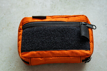 Orange tactical pouch with black velcro panel and zipper pocket, placed on light background.