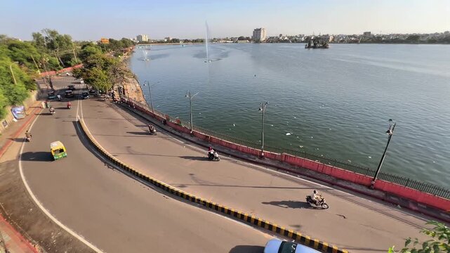 Timelapse of busy traffic movement near Kishore Sagar Lake Kota with vehicles moving along city road and urban skyline, showing modern transportation and infrastructure.