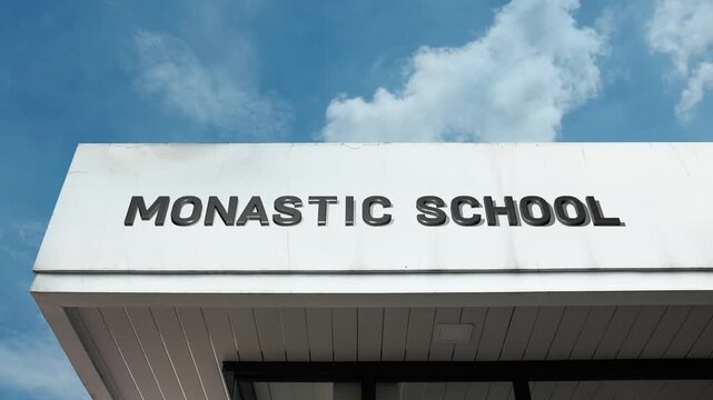 A monastic school word sign displayed on a serene educational building under a clear blue sky, symbolizing religious instruction, spiritual learning, and traditional education