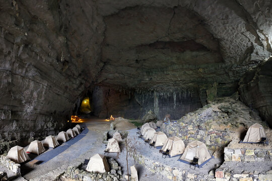 Aerial view of tents in the Ditang Caves, a cavernous space with textured rock walls and dim lighting, Ditang Caves, Guizhou, China.