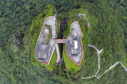 Aerial view of the iconic Fanjingshan Temple splits the sky atop a verdant, mist-shrouded peak, a testament to faith and nature's grandeur, Fanjingshan, Guizhou, China.
