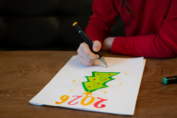 A girl draws a Christmas tree with a marker