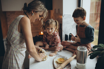 A mother and her children are preparing delicious food in the kitchen on the eve of the holiday. Children and their mother are cooking