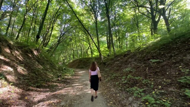 A girl is walking in a summer park.