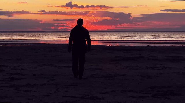 A guy walks into the sunset on the seashore