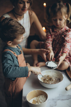 A mother and her children are preparing delicious food in the kitchen on the eve of the holiday. Children and their mother are cooking