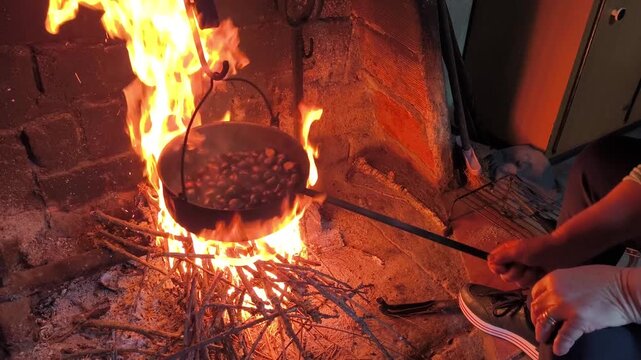 V&iacute;deo de uma mulher a assar castanhas numa fogueira r&uacute;stica com um assador de ferro numa cozinha rural