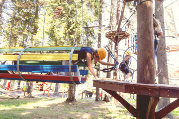 Girl in helmet navigating aerial obstacle course at adventure park
