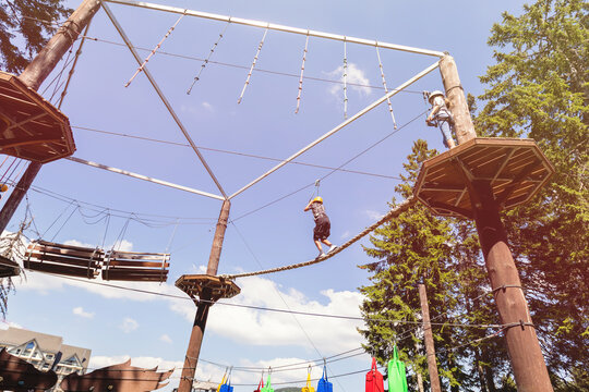 Child on high wooden platform at aerial adventure park ropes course