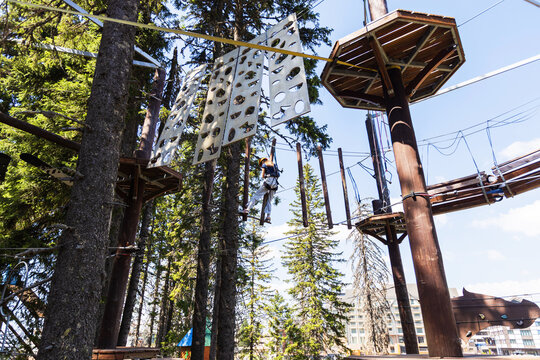 Girl in helmet navigating aerial obstacle course at adventure park