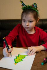 A girl draws a Christmas tree with a marker