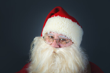 Close-up portrait of an authentic Santa Claus wearing glasses and looking at the camera. Christmas concept.