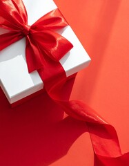 Elegant gift box with red ribbon on a vibrant, red background.