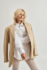 Stylish young blonde woman showcases winter fashion in modern white studio setting