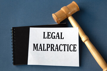 LEGAL MALPRACTICE - words on a white sheet on a black notebook with a judge's gavel in the background