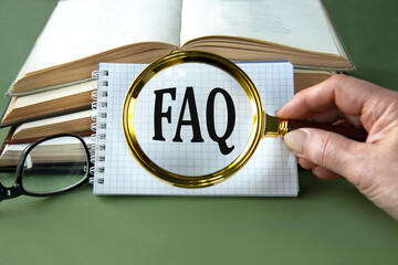 A woman's hand holds a magnifying glass over the word FAQ on a green background with books