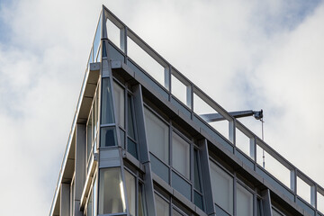Fototapeta premium Sharp Angular Corner of a Modern Building Against a Cloudy Sky
