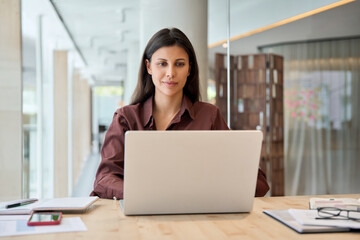 Obraz premium Focused ceo businesswoman professional employee or young student studying using pc doing work. Latin hispanic business woman financier manager working on laptop computer in office, looking at screen