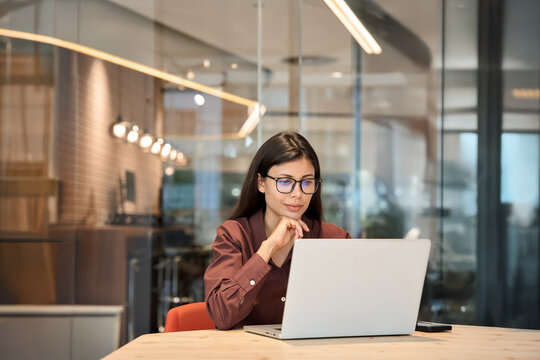 Young businesswoman professional employee using pc doing online banking trade analysing at workplace. Latin hispanic middle age business woman thinking working on laptop computer in office. Copy space