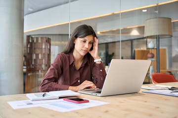 Confused young trader businesswoman looking disappointed at laptop pc computer screen having...