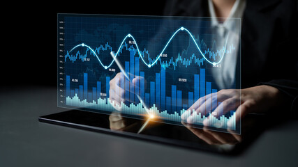 A business professional uses a tablet to analyze financial data with digital graphs and charts in a modern office environment, illustrating advanced analytics techniques. Scalp