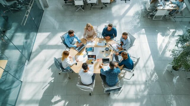 Business team working together around round table in modern glass office discussing strategy and new ideas