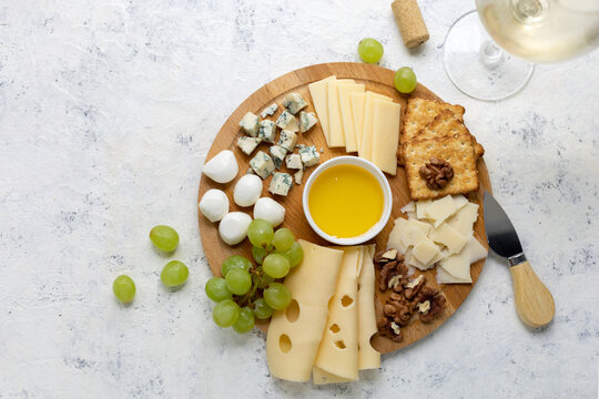 Gourmet cheese platter with grapes, nuts, and honey on rustic wooden board - Powered by Adobe