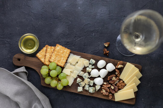 Gourmet cheese and wine pairing with crackers, grapes, and nuts on rustic board