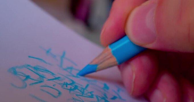 Close-up shot of hand drawing abstract pattern on paper with blue pencil.