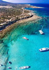 Aerial view of tourists swimming and enjoying the turquoise waters of Chrysochou bay in the blue lagoon, Akamas peninsula, Cyprus